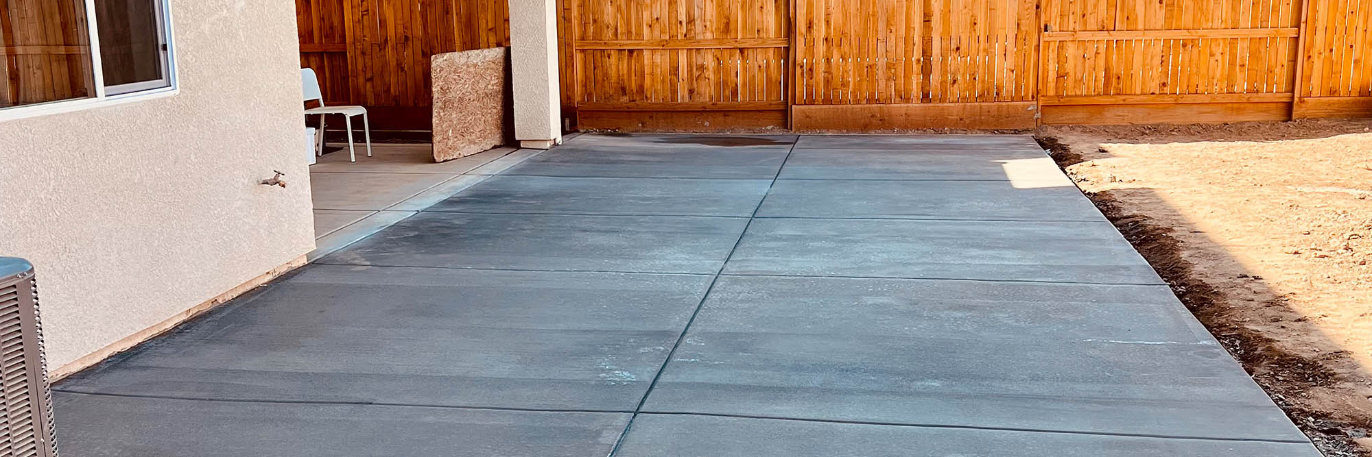 a backyard concrete patio surrounded by a new six foot wood fence